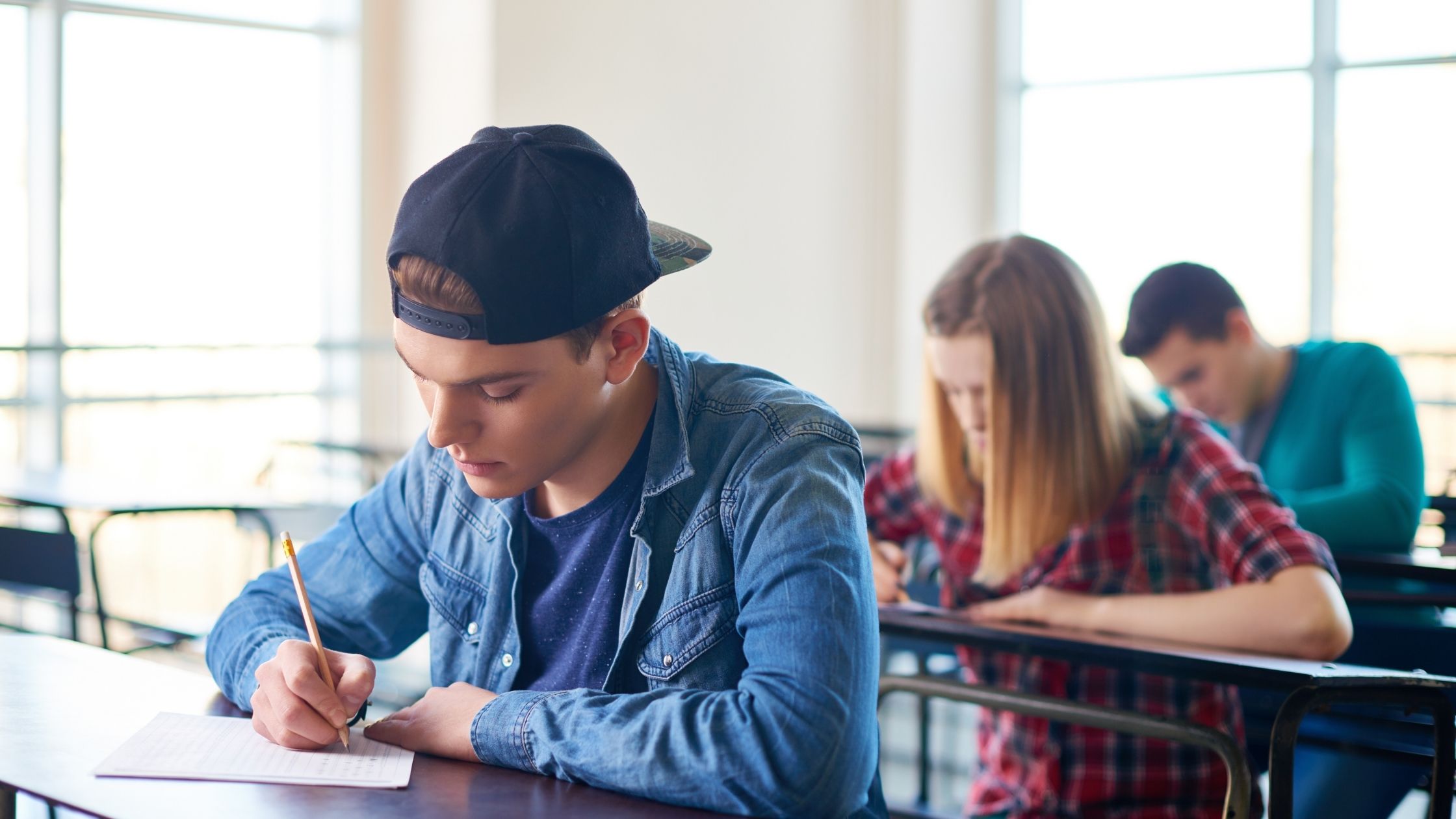 a boy wearing blue shirt writing their exam